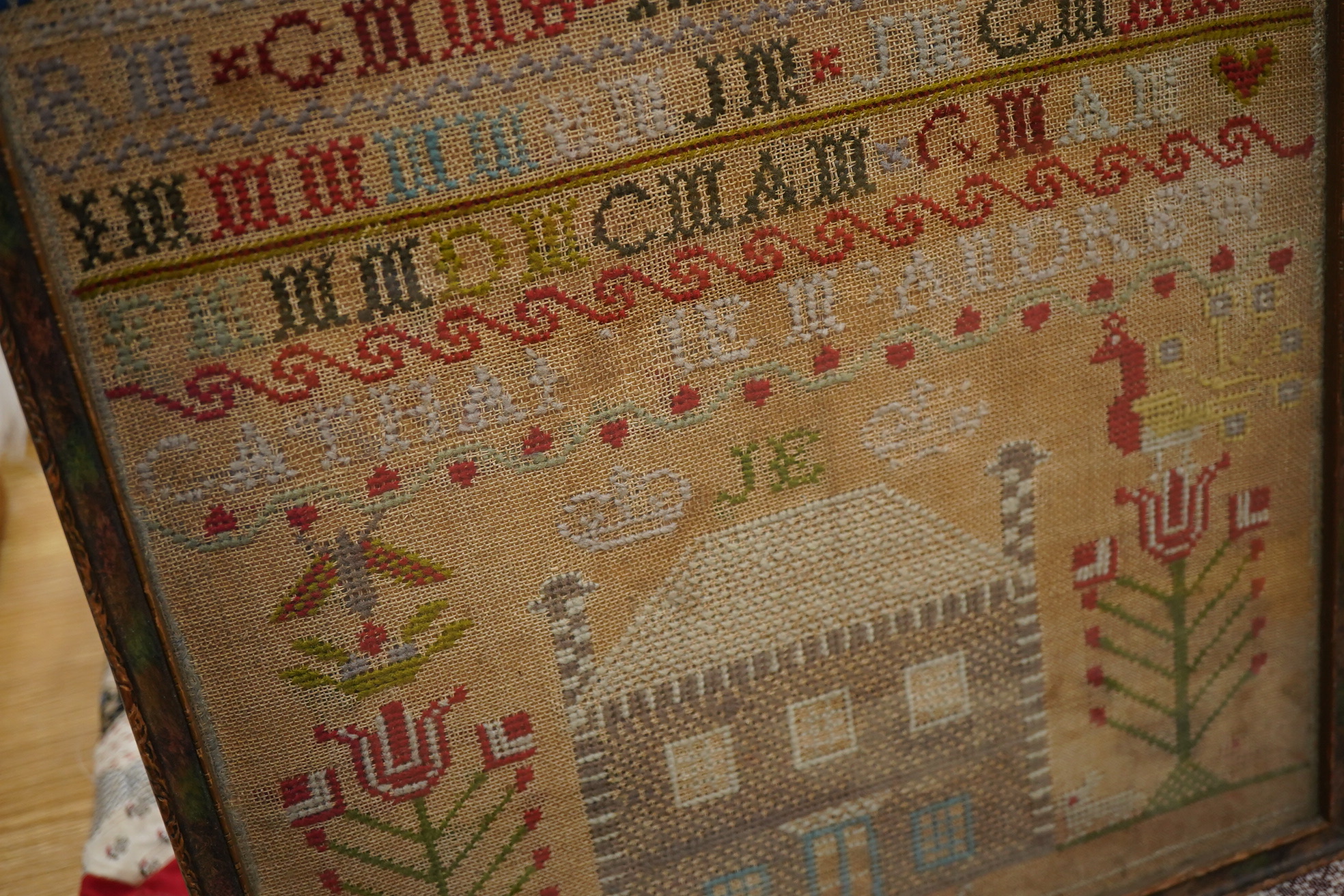 A 19th century alphabet cross stitch sampler, worked with a large house motif - 41cm x 29cm, together with a 19th century unfinished cotton patch worked central panel. Condition - the sampler has some stains but the thre